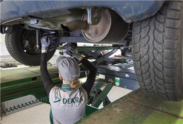 Eine KFZ-Ingenieurin kontrolliert in einer Dekra-Werkstatt ein Fahrzeug bei einer Hauptuntersuchung