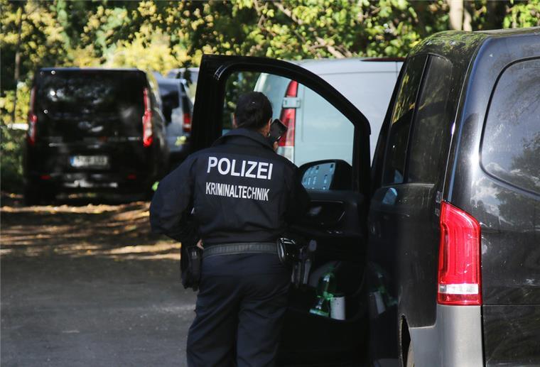 Eine Kriminaltechnikerin steht in der Nähe vom S-Bahnhof Hohenschönhausen neben Fahrzeugen der Polizei. 