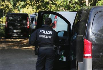 Eine Kriminaltechnikerin steht in der Nähe vom S-Bahnhof Hohenschönhausen neben Fahrzeugen der Polizei. 