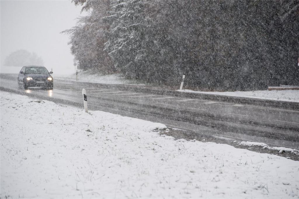 Die Bayern waren zuerst dran: Ein Auto fährt am Sonntag der Nähe von Wolfratshausen über eine verschneite Landstraße.