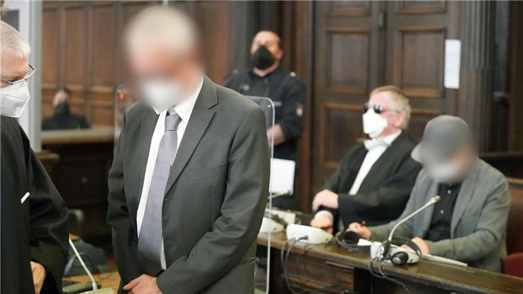Die beiden angeklagten Ärzte (hinten r und vorne 2.v.l) warten im Sitzungssaal des Landgerichts.