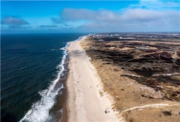 Einige Menschen laufen bei strahlendem Sonnenschein über den Sandstrand der Ostseite der Insel Sylt.
