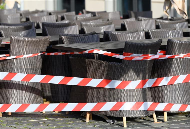 NGG: Gastro-Beschäftigte leiden hart unter Lockdown Ein Absperrband umgibt Tische und Stühle vor einem Restaurant.