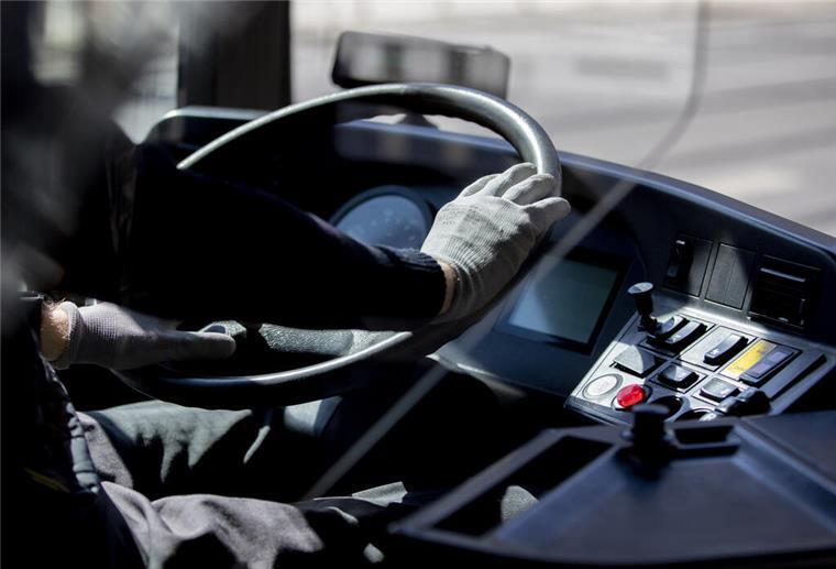 Ein Busfahrer hält das Lenkrad mit Handschuhen.