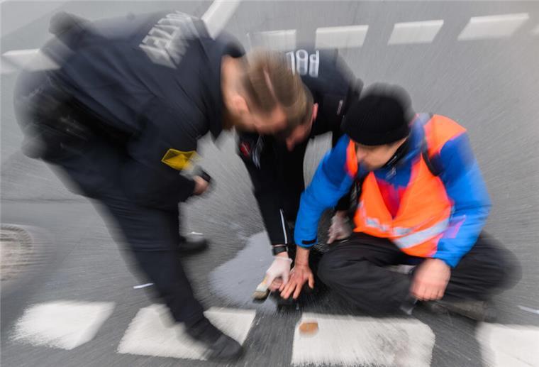 Kosten für Polizeieinsätze: Klimakleber sollen zur Kasse gebeten werden Polizisten neben Demonstrant