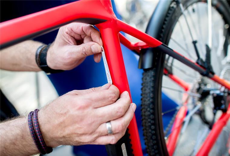 Besucher der Zweiradmesse können ihr Fahrrad kostenlos registrieren lassen Ein Polizist klebt eine Plakette mit einer registrierten Nummer auf den Rahmen eines Fahrrads.