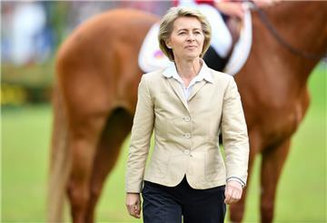 Ursula von der Leyen steht vor einem Turnierpferd mit Reiter