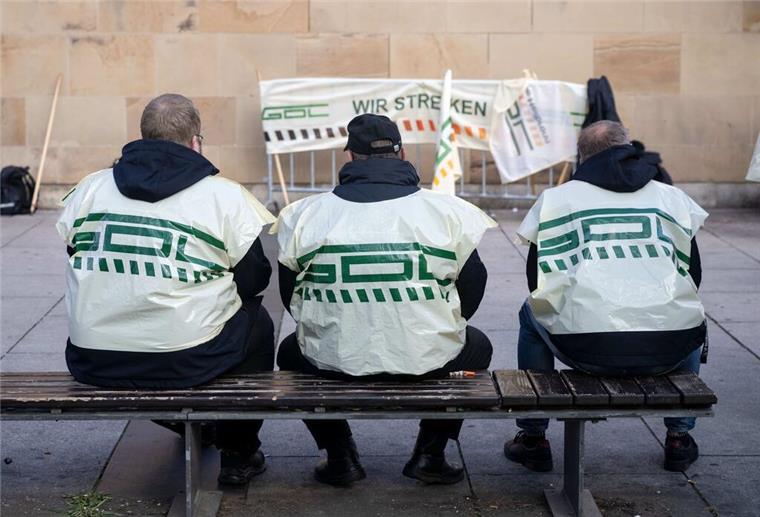 Tarifstreit von Bahn und GDL: Kommt jetzt der Streik an Weihnachten? Teilnehmer eines Warnstreiks der Gewerkschaft Deutscher Lokomotivführer (GDL) sitzen vor dem Hauptbahnhof auf einer Bank.