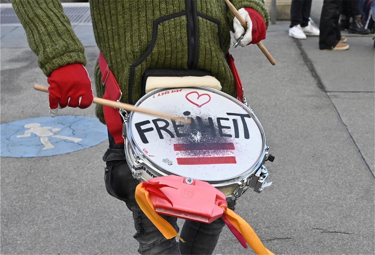 Ein Teilnehmer der Kundgebung «Nein zur Impfpflicht - Neuwahlen jetzt» trommelt auf einer Trommel mit der Aufschrift «Freiheit». 