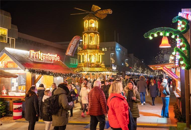 Bremerhavener Weihnachtsmarkt ist eröffnet Menschen schlendern an Ständen eines Weihnachtsmarktes vorbei.