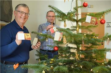 Die ersten Kärtchen hängen schon (von links): Johann Haack und Pastor Dirk Glanert hängen fleißig die Weihnachtswünsche der Kinder in die Zweige. 
