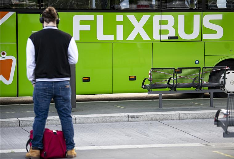 Flixbus stellt Betrieb vorübergehend ein Mann steht vor einem grünen Flixbus.