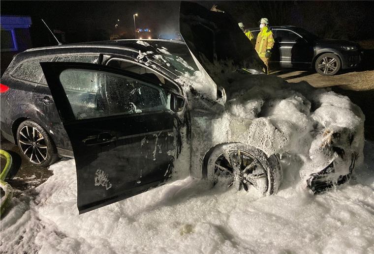 Ein ausgebranntes, schwarzes Auto voller Löschschaum.
