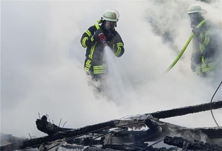Feuerwehr kann Schuppen im Spadener Moor nicht mehr retten Feuerwehrleute stehen im Qualm und löschen einen Schuppen