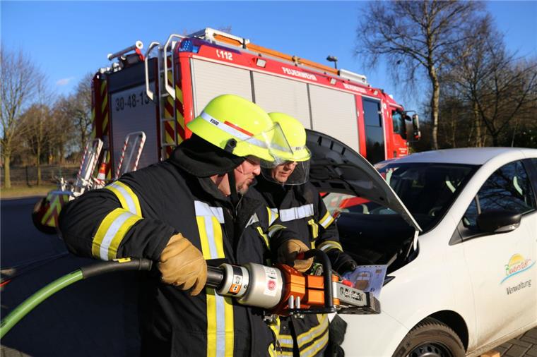 Unter Spannung: Beverstedter Feuerwehr stellt sich auf Elektroautos ein Die Feuerwehrleute Carsten Salinski (links) und Axel Brünjes beim Einsatz am Elektro-Auto. Während Salinski schon die Rettungsschere bereithält, studiert Brünjes das Rettungsdatenblatt des Flitzers. Dort ist vermerkt, wo die gefährlichen Hochvolt-Leitungen verlaufen. Fotos (2) Gehrke