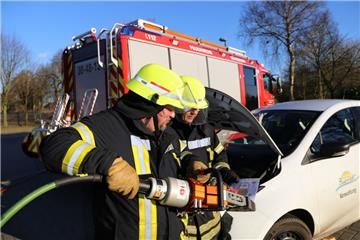 Die Feuerwehrleute Carsten Salinski (links) und Axel Brünjes beim Einsatz am Elektro-Auto. Während Salinski schon die Rettungsschere bereithält, studiert Brünjes das Rettungsdatenblatt des Flitzers. Dort ist vermerkt, wo die gefährlichen Hochvolt-Leitungen verlaufen. Fotos (2) Gehrke