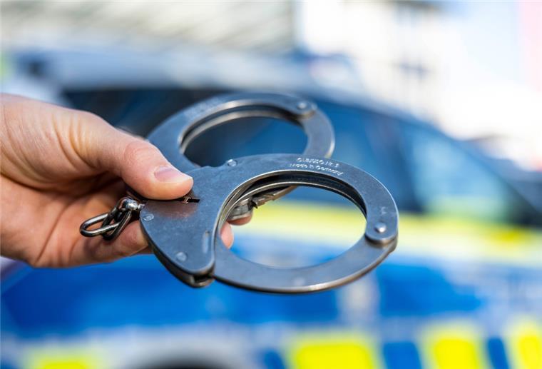 Hannover: Polizei greift Frau auf, die 2003 untergetaucht ist Eine Hand hält Handschellen vor einen Streifenwagen der Polizei.