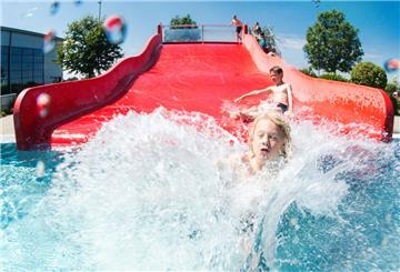 Nordrhein-Westfalen, Düsseldorf: Zwei Kinder springen von der Wasserrutsche ins Schwimmbecken.