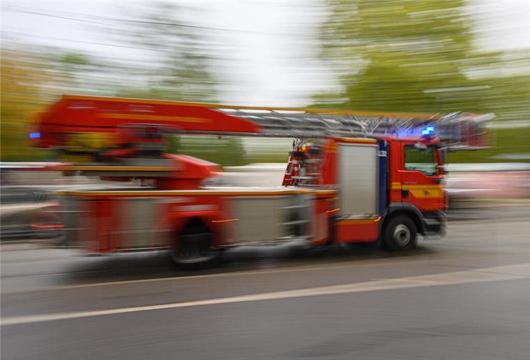 Ein Feuerwehrfahrzeug mit Drehleiter fährt in der Innenstadt zu einem Einsatz.