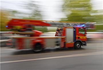 Ein Feuerwehrfahrzeug mit Drehleiter fährt in der Innenstadt zu einem Einsatz.