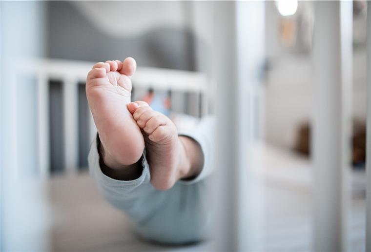 Die Füße eines Babys in einem Kinderbett.