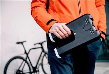 Ein Mann hält einen Fahrradakku in der Hand.