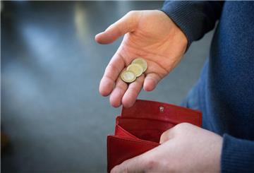 Eine Hand greift Münzen aus einer Geldbörse.