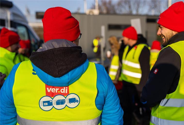 Streikende stehen vor einem Gebäude des Paketdienstleisters DHL. 