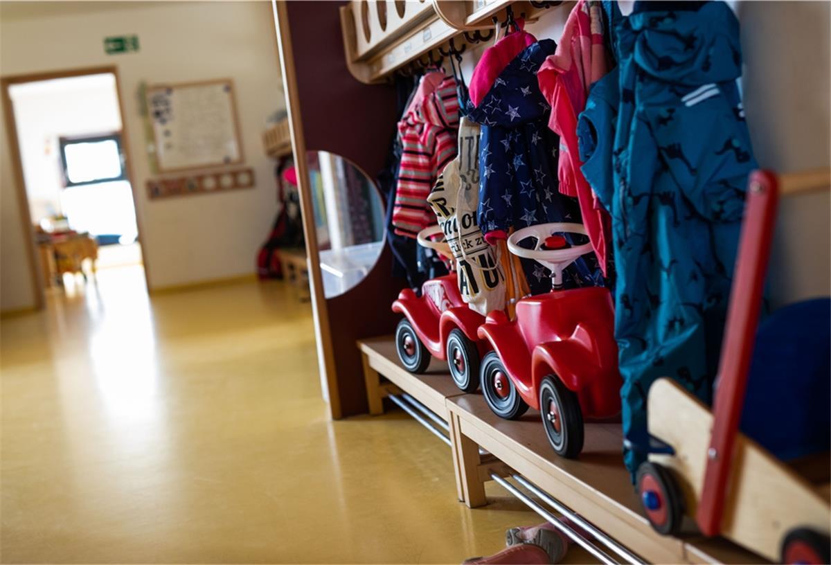 Bobbycars stehen unter Jacken von Kindern, die an einer Garderobe einer Kindertagesstätte (Kita) hängen