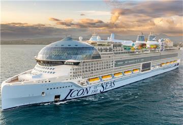 Die Icon of the Seas liegt im Wasser vor einer Großstadt. Sie ist das größte Kreuzfahrtschiff der Welt.
