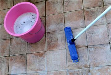  Ein Eimer mit Seifenwasser und ein Schrubber werden für das Reinigen eines Fliesenbodens benötigt