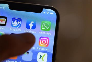 Eine Hand hält ein iPhone, auf dem Sozial Media Apps dargestellt sind
