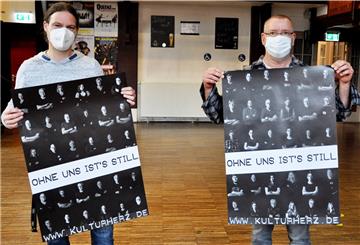 Die Jahnhallenmitarbeiter Sven Lüdke (links) und Yeti Mansena präsentieren die Kulturherz-Plakate. Zu sehen sind darauf Menschen aus Nordneham, die die lokale Kunst und Kultur prägen.