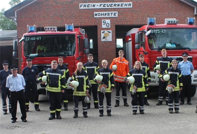 Sie beherrschen das Einmaleins der Feuerwehr Junge Feuerwehrleute vor zwei Feuerwehrfahrzeugen