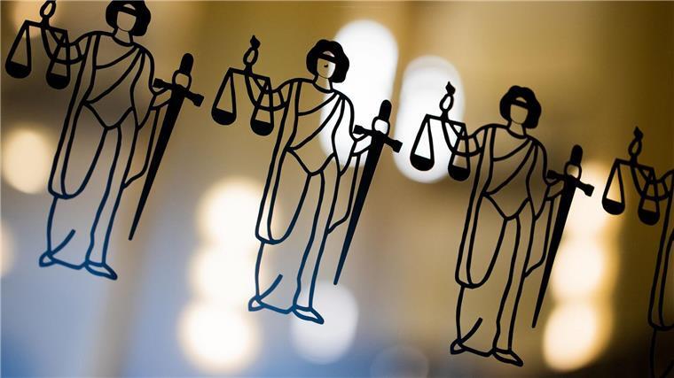 Prozess um großangelegten Betrug mit Urlaubsreisen gestartet Die Justitia ist an einer Scheibe am Eingang zum Oberlandesgericht zu sehen.
