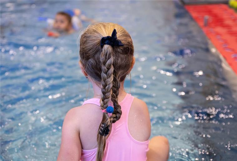 Kostenlose Schwimmkurse für Kinder in Bremerhaven Ein Mädchen sitzt am Beckenrand eines Schwimmbades.