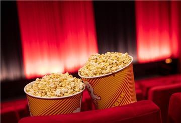 Popcorn steht zwischen den Sitzreihen in einem Kino.