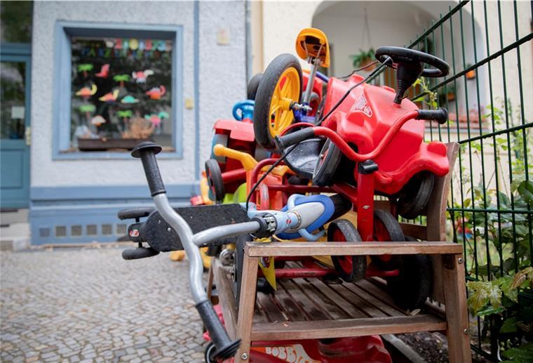 Bobby-Cars, andere Spielautos und Gefährte für Kinder liegen angeschlossen vor einer Kita.