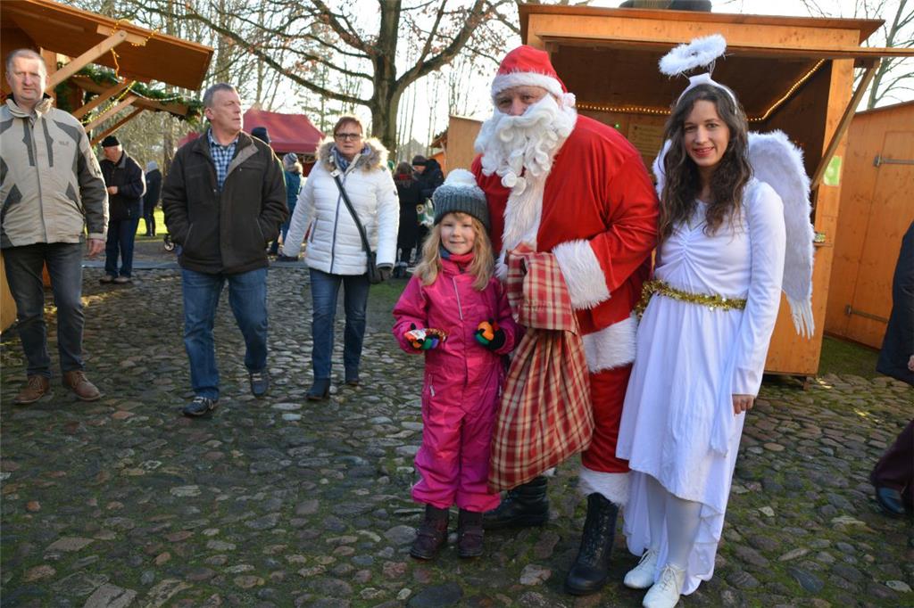 Die kleine Emma sorgte dafür, dass der Sack vom Weihnachtsmann etwas leichter wurde. Der hatte zur Unterstützung Engel Carina nach Bad Bederkesa mitgebracht. Foto: Scheiter