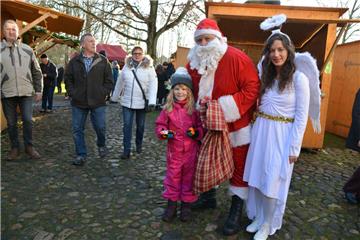 Die kleine Emma sorgte dafür, dass der Sack vom Weihnachtsmann etwas leichter wurde. Der hatte zur Unterstützung Engel Carina nach Bad Bederkesa mitgebracht. Foto: Scheiter
