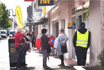 Ein Security-Mitarbeiter vor EWE lehnt an einer Hauswand.