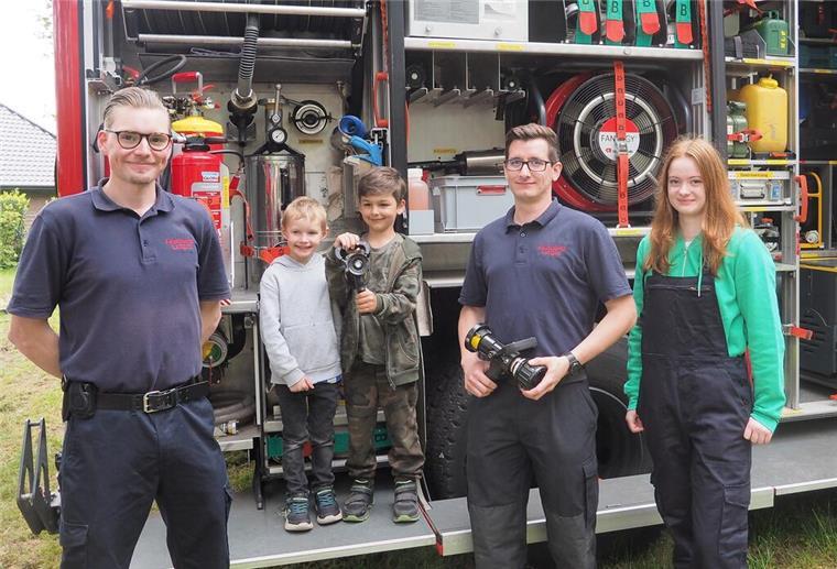 Feuerwehr und Diesellok beim Bahnsteigfest in Langen Zwei Jungen von 6 und 4 Jahren stehen zusammen mit zwei Feuerwehrmännern und einem jugendlichen Mitglied der Jugendwehr vor einem Löschfahrzeug.