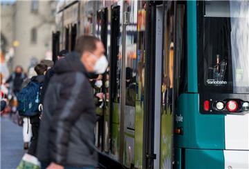 Fahrgäste mit FFP2-Masken steigen in eine Straßenbahn in der Innenstadt ein. 