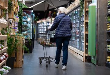 Eine Frau geht mit ihrem Einkaufswagen durch einen Super