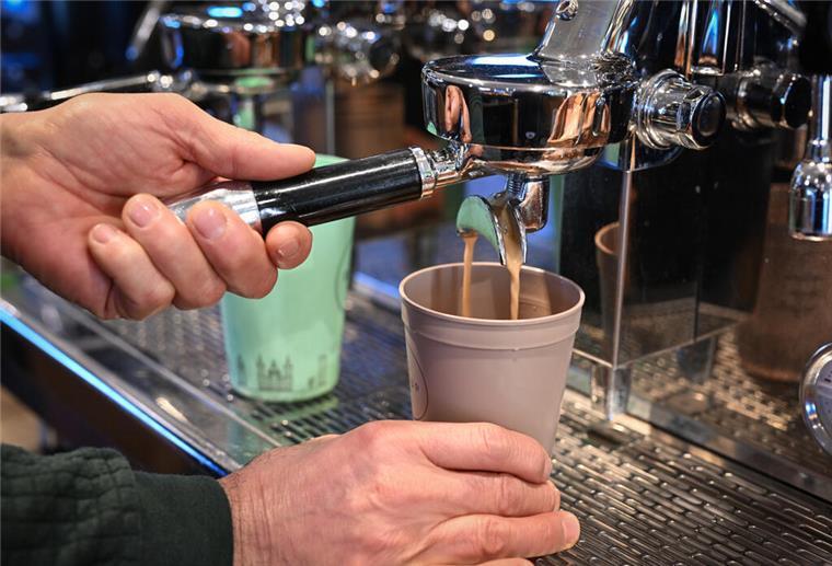 Mehrwegpflicht: So wollen die Grünen die Umsetzung durchsetzen Ein Mitarbeiter eines Bio-Ladens bereitet einen Kaffee zu, der in einen Mehrwegbecher fließt.