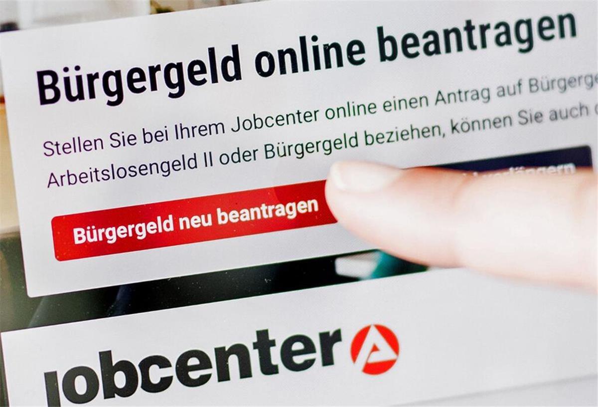 Eine Frau tippt auf einem Tablet auf einen Link zum Beantragen des Bürgergeldes im Kundenbereich im Jobcenter Berlin-Mitte.