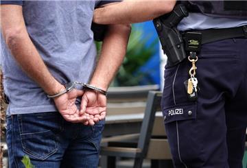 Ein Mann steht in Handschellen neben einem Polizisten. 