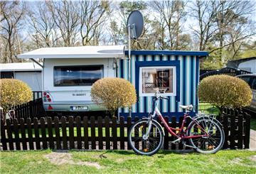 Ein Fahrrad steht an einem Gartenzaun vor einem Wohnwagen auf dem Campingplatz der Familie Wilken an der Thülsfelder Talsperre. Die Nachfrage nach Dauercampingplätzen in Niedersachsen ist größer als das Angebot.
