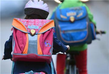  Kinder mit Fahrradhelmen radeln zur Schule. 