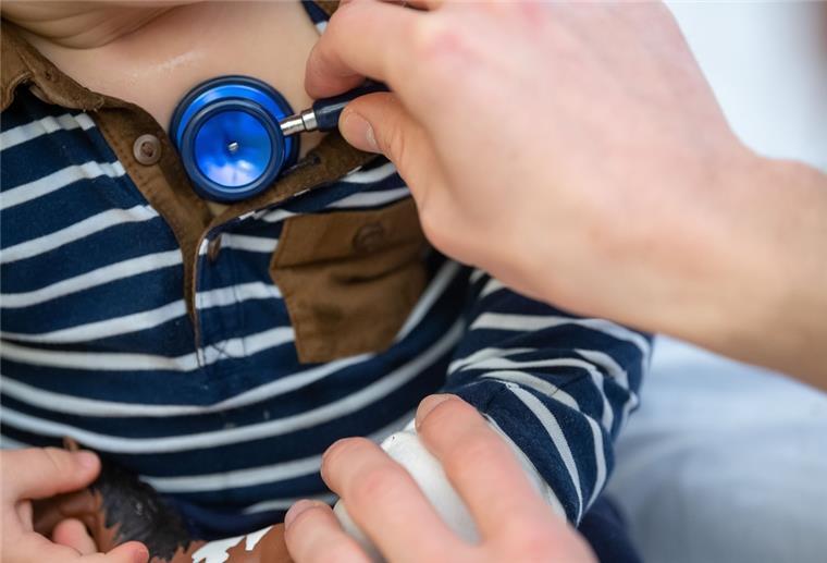 Kinderarztpraxen am Limit: „Infektwelle nicht der Grund“ Ein Arzt untersucht ein Kind mit einem Stethoskop.